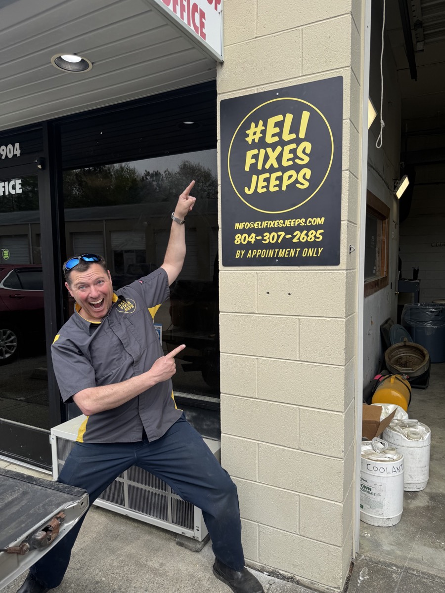 Eli standing with the EFJ shop sign